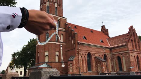 holding rosary in hands with church in the background