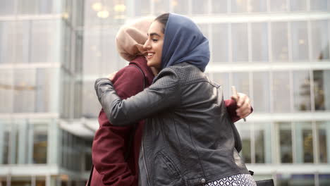 two british muslim women friends meeting outside office