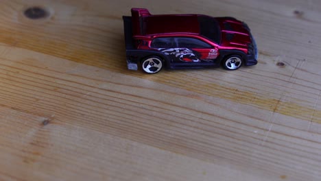 red toy car on a wooden board with dark background