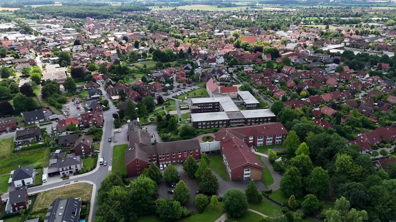 Picturesque American neighborhood with green trees on streets in summer. Aerial wide shot. Historic hospitals building and red brick roofs of homes in United States. Quiet scene
