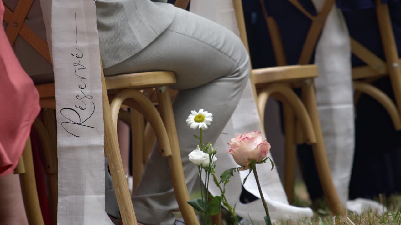 Guest sitting on wooden chairs on wedding day