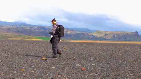 Explorador-Islandés-Caminando-Por-Una-Vasta-Llanura-Negra,-Un-Icónico-Telón-De-Fondo-Montañoso