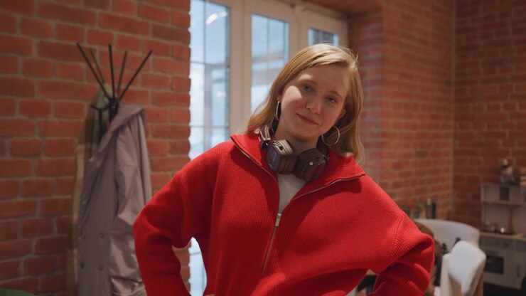Young Woman Puts Headphones Around Neck and Smiles at Camera