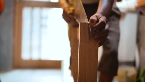 primer plano de un carpintero cortando un trozo de madera con sierra manual, carpintero usando una sierra transversal, carpintero trabajando en su taller haciendo muebles