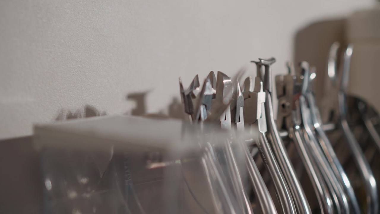 Close up of various metal orthodontic tools arranged in row highlighting their distinct shapes and shiny surfaces. scene features soft lighting that emphasizes reflective texture details