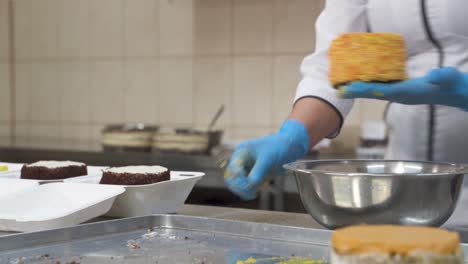 woman chef decorating cake confetti close-up. professional chef in gloves in confectionery shop cooking cake with cream, tasty dessert