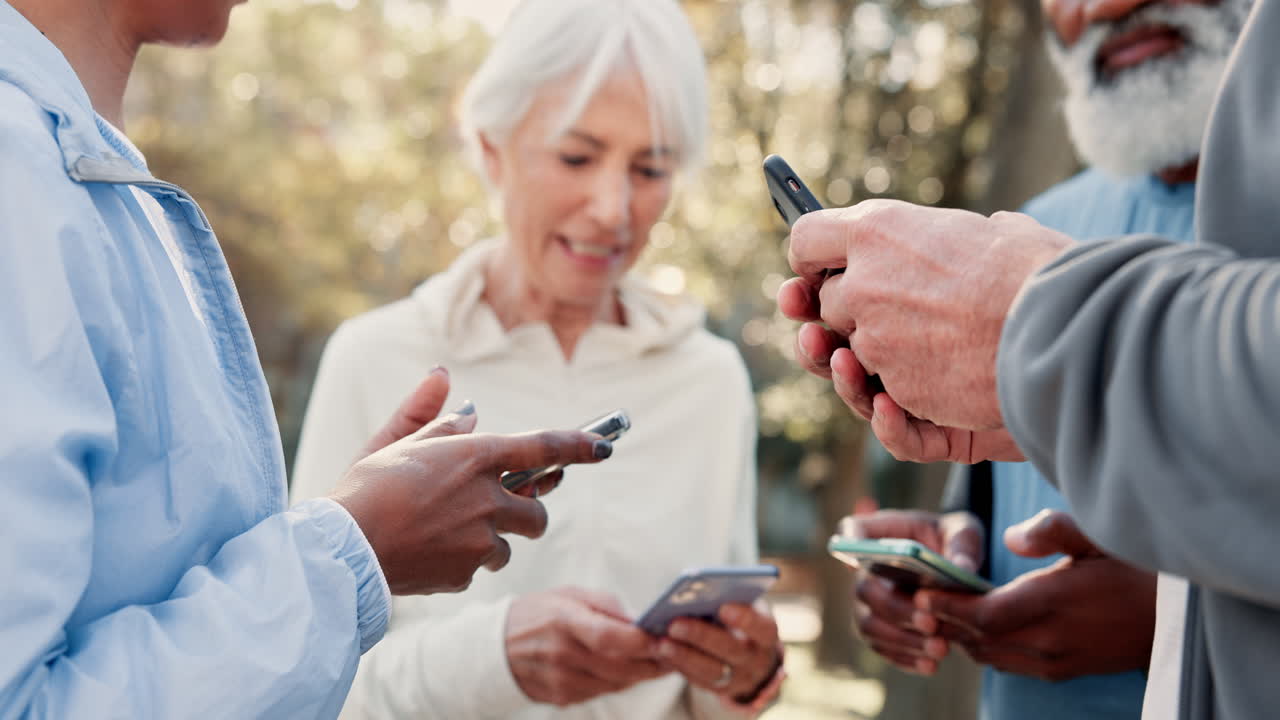 Gruppo di anziani che usano smartphone in un parco.