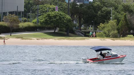 a boat moves along a waterfront park