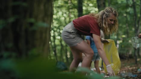 madre caucásica con hijas limpiando el bosque de basura.
