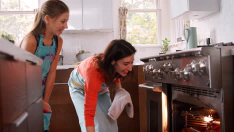 Madre-Sacando-Pan-Del-Horno-Mientras-Su-Hija-Observa.