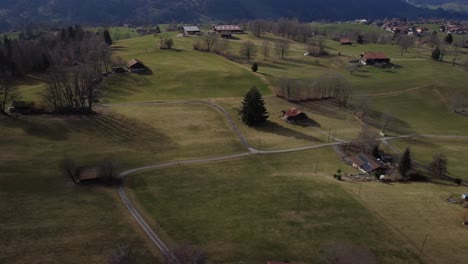 Panning-aerial-view,-Swiss-farmland-and-sparse-village-buildings