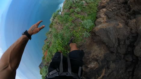 POV-shot-of-a-man-carefully-hiking-on-a-narrow-and-dangerous-path-on-the-side-of-Quebrada-do-Negro-in-Madeira