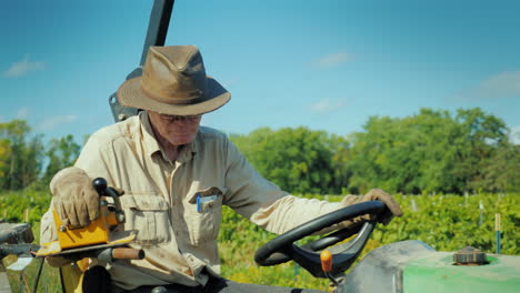 the farmer in the hat works on a small tractor