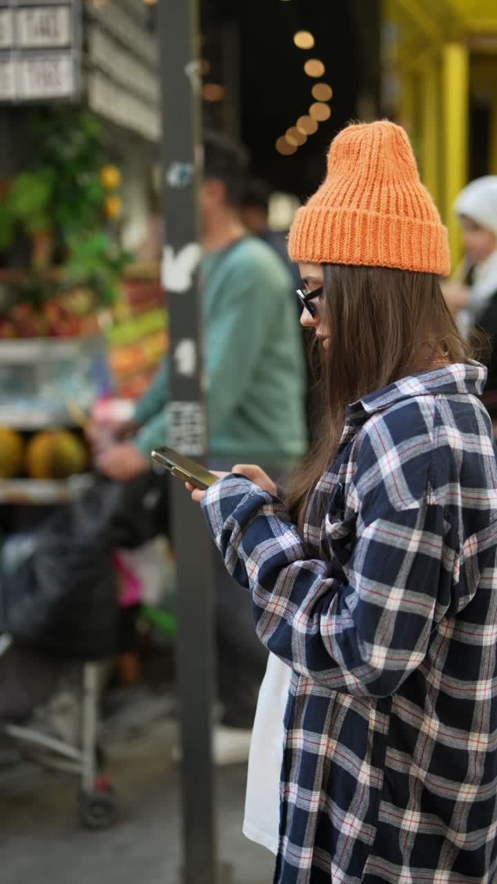 молодая женщина использует телефон на городском рынке