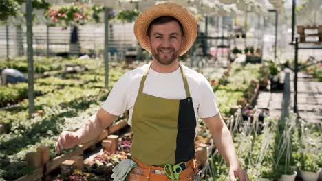 portrait of a young male gardener in apron and hat looking at camera