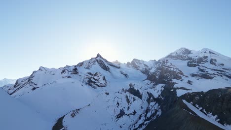 Beautiful-scenic-aerial-of-snow-covered-alpine-mountain-range-glacier-peak-top-on-a-blue-sky-morning