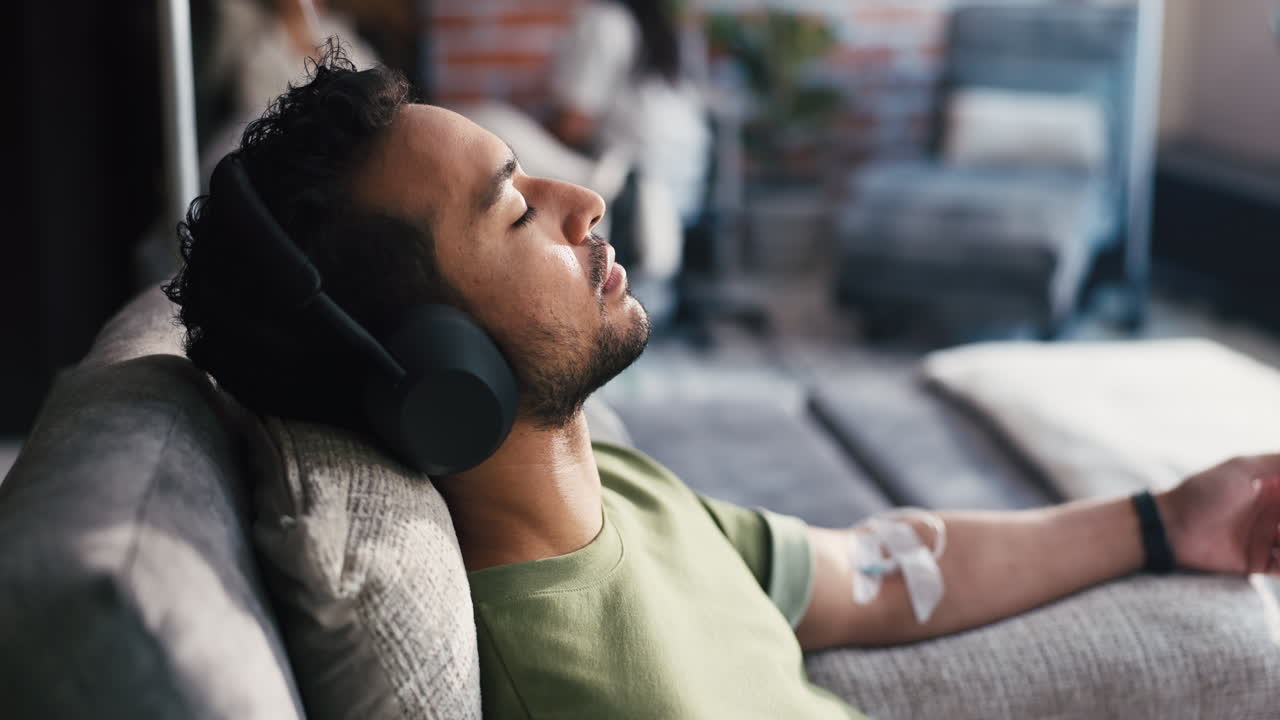 Man with Headphones Relaxing on Couch with IV Drip