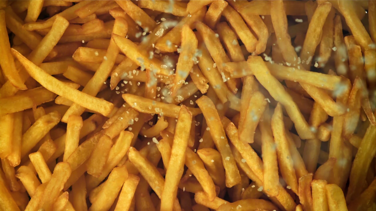 Salz fällt auf goldene Pommes Frites.