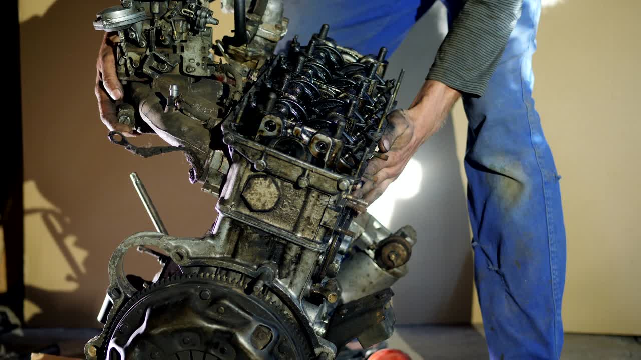 mecánico de automóviles recoge un motor de coche viejo renovado