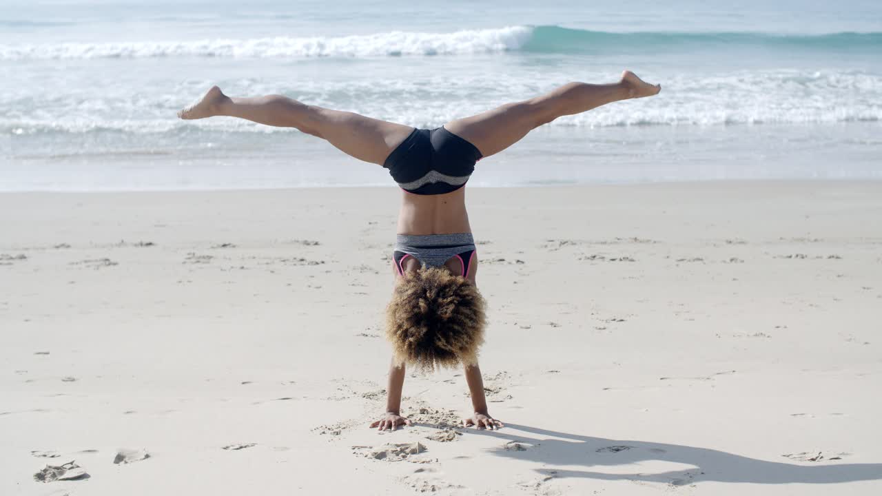 chica haciendo un handstand en una playa