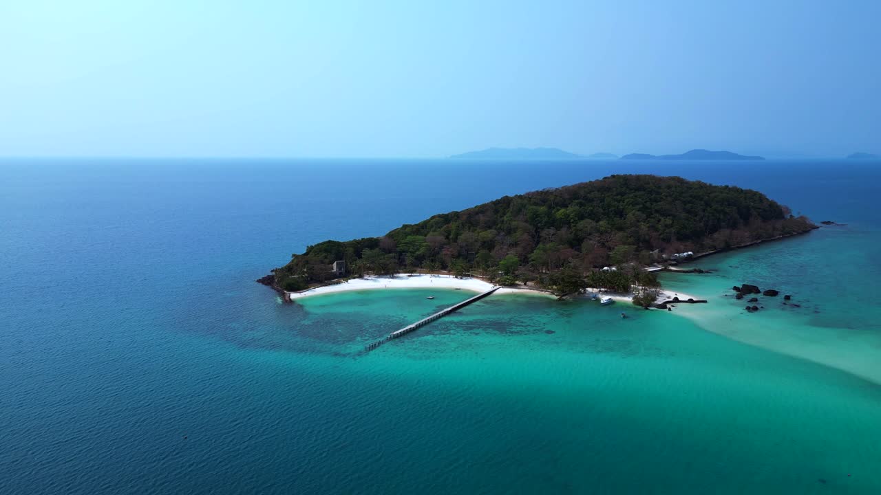 Koh Kham Island with its green tropical vegetation surrounded by crystal clear turquoise waters, Thailand. Perfect aerial view flight static tripod hovering drone