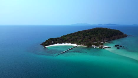 koh kham island with its green tropical vegetation surrounded by crystal clear turquoise waters, thailand. perfect aerial view flight static tripod hovering drone
