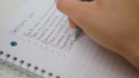 woman's hand writing self-care list. close up