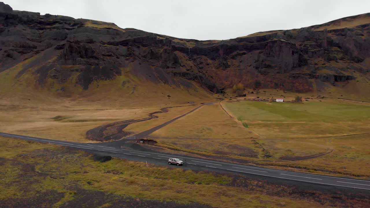 Vista aerea 4K di un'auto SUV parcheggiata su una strada islandese con uno splendido paesaggio montano nella campagna, Islanda, Europa, ripresa orbitale da sinistra a destra.