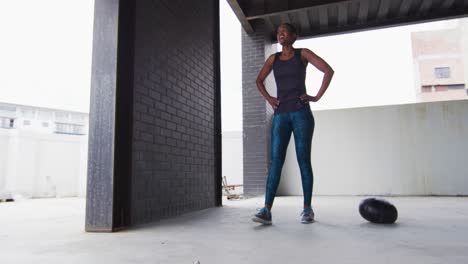 african american woman resting after exercising with medicine ball in an empty urban building