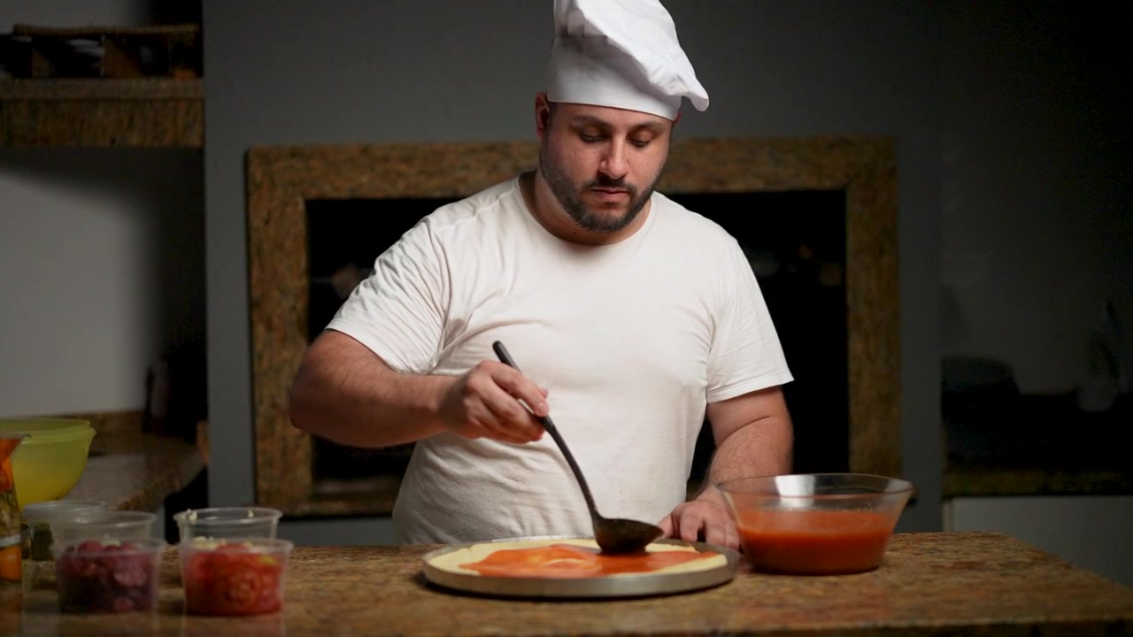 Chef che spalma salsa di pomodoro fresco sull'impasto, evidenziando autentiche tecniche di cucina italiana.