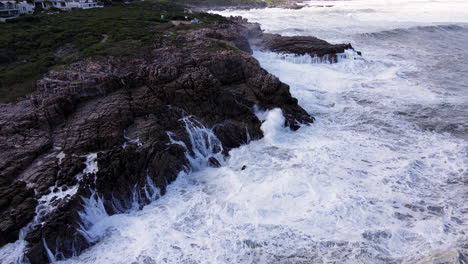 Meerwasser-Strömt-Schroffe-Felsen-An-Der-Küste-Von-Hermanus-Hinunter,-Turbulenter-Ozean,-Drohne