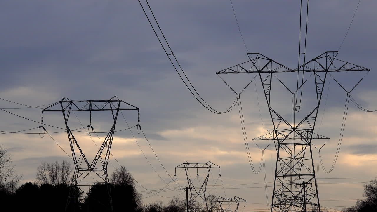 Electrical towers against somber early evening cloudy sky