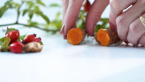 close up, woman's hands opening up turmeric root on kitchen table