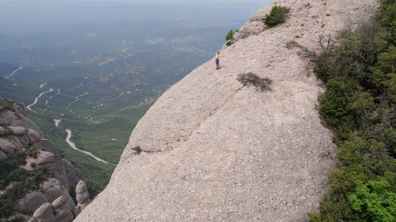 mujer joven haciendo ejercicio en la cima de la montaña, toma cinematográfica de un avión no tripulado realizando una órbita, concepto de bienestar y salud, monasterio de montserrat, barcelona
