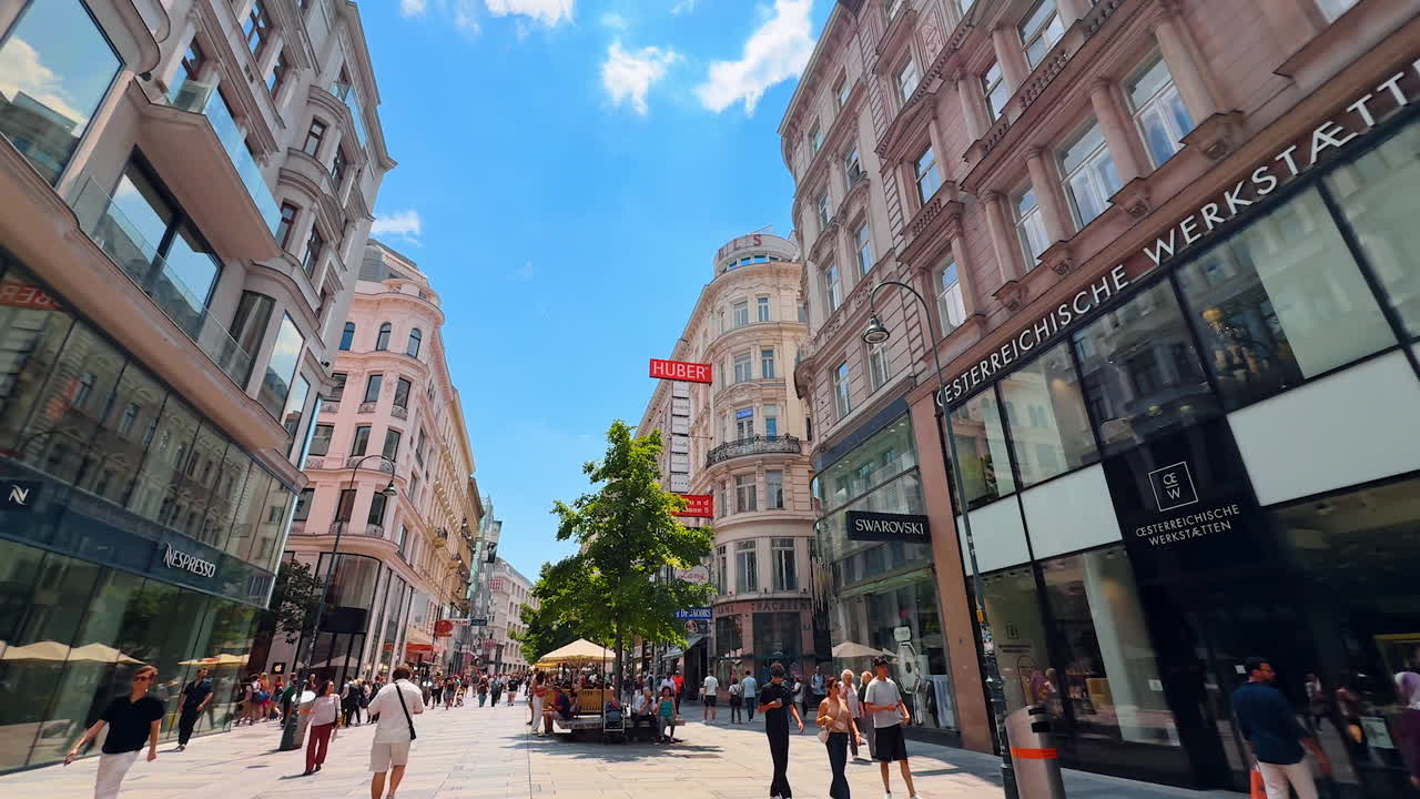 Vienna, Austria - June 9, 2025: Vibrant streets of Vienna. Tourists wander through busy streets in the heart of Wien, enjoying shops and cafes under a clear blue sky