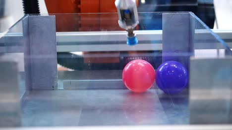 robot manipulando una pelota en un recinto transparente