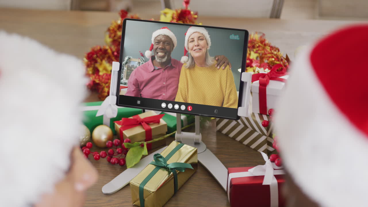 pareja diversa con sombreros de santa teniendo llamada de video de tableta con pareja diversa