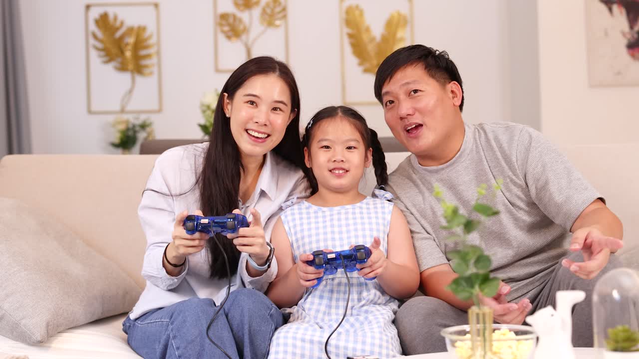 A family enjoys playing video games together on a couch, creating a warm and joyful atmosphere with bright lighting