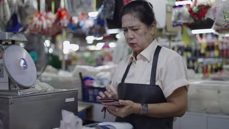 woman at a market stall using a mobile phone