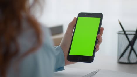 zoom in shot of unrecognizable little girl holding smartphone with green chroma key screen and watching lesson, close up