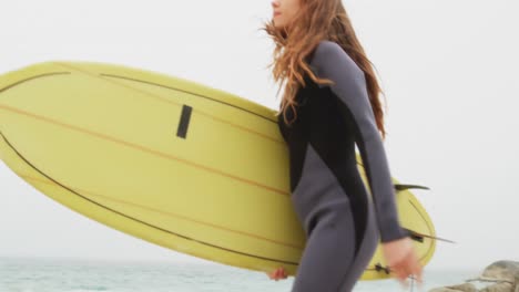 Side-view-of-Caucasian-female-surfer-running-with-surfboard-on-the-beach-4k