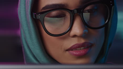 retrato en primer plano hermosa mujer de negocios musulmana usando una tableta trabajando hasta tarde navegando por internet haciendo lluvia de ideas mirando la información en la pantalla usando gafas