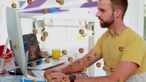 Multiple-face-emojis-floating-against-man-using-computer-at-office