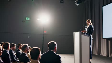 a speaker presents at a conference, captured from a low-angle, emphasizing authority