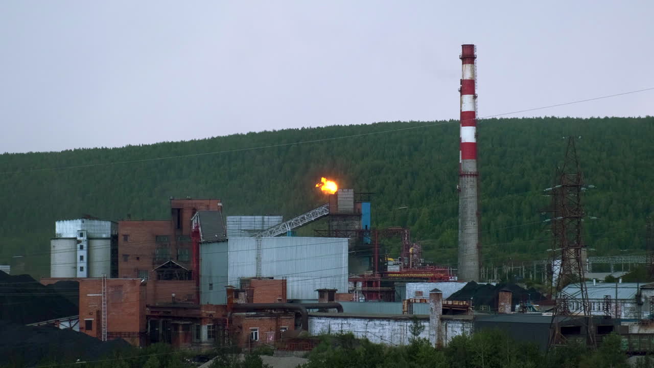 planta industrial con llamas y chimeneas de humo