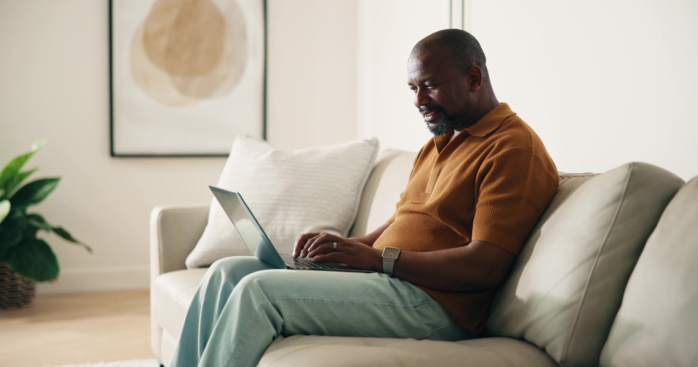 Mature African American Man Working on Laptop on Sofa