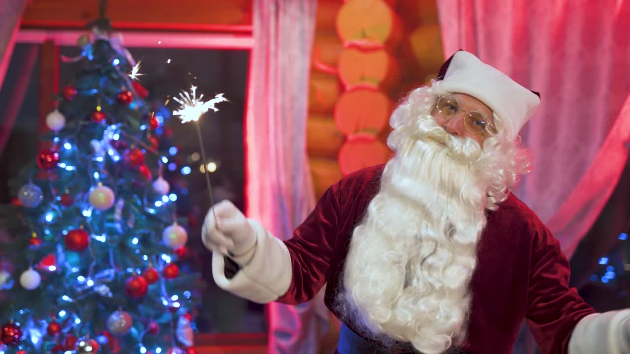 Happy Santa Claus is dancing near the Christmas tree with sparklers. House with New Year's decorations on the eve of the holiday