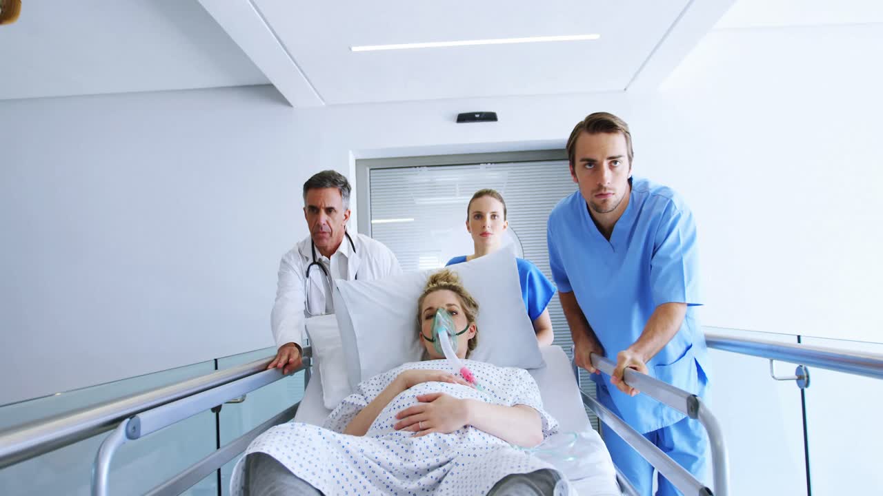 Équipe di medici che accompagna una donna incinta in sala operatoria