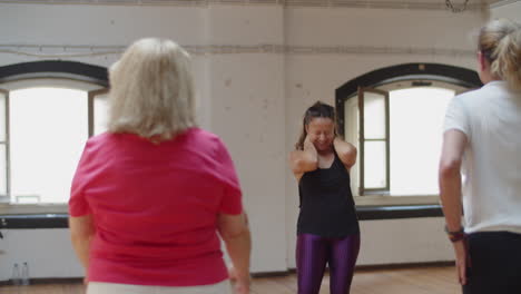 Happy--female-dance-teacher-talking-with-group-during-class