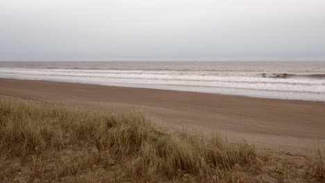 Mirando-Por-Encima-De-Las-Dunas-De-Arena-Marram-Hierba-Con-La-Playa-Del-Mar-Más-Allá-En-Ingoldmells,-Skegness-Beach